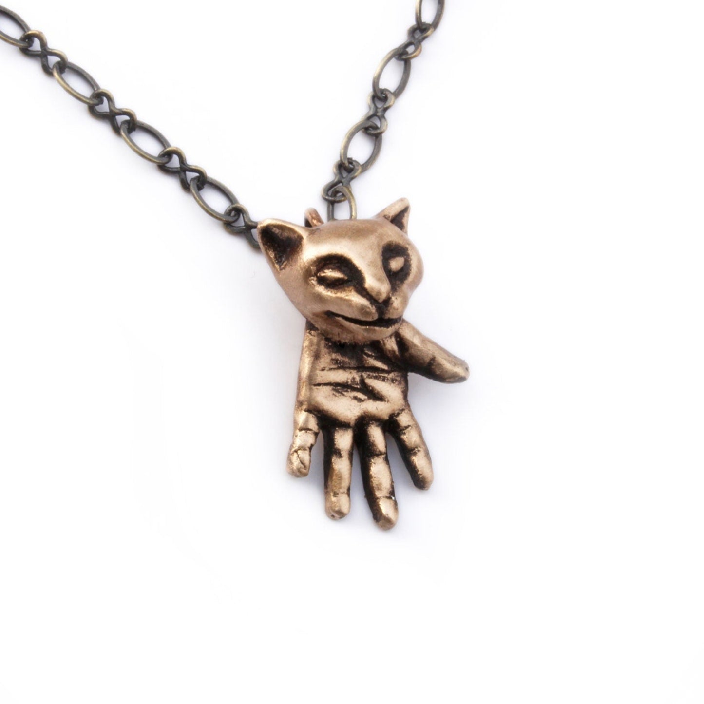 Bronze cat-shaped pendant, the creature have a cat head and a hand as a body 