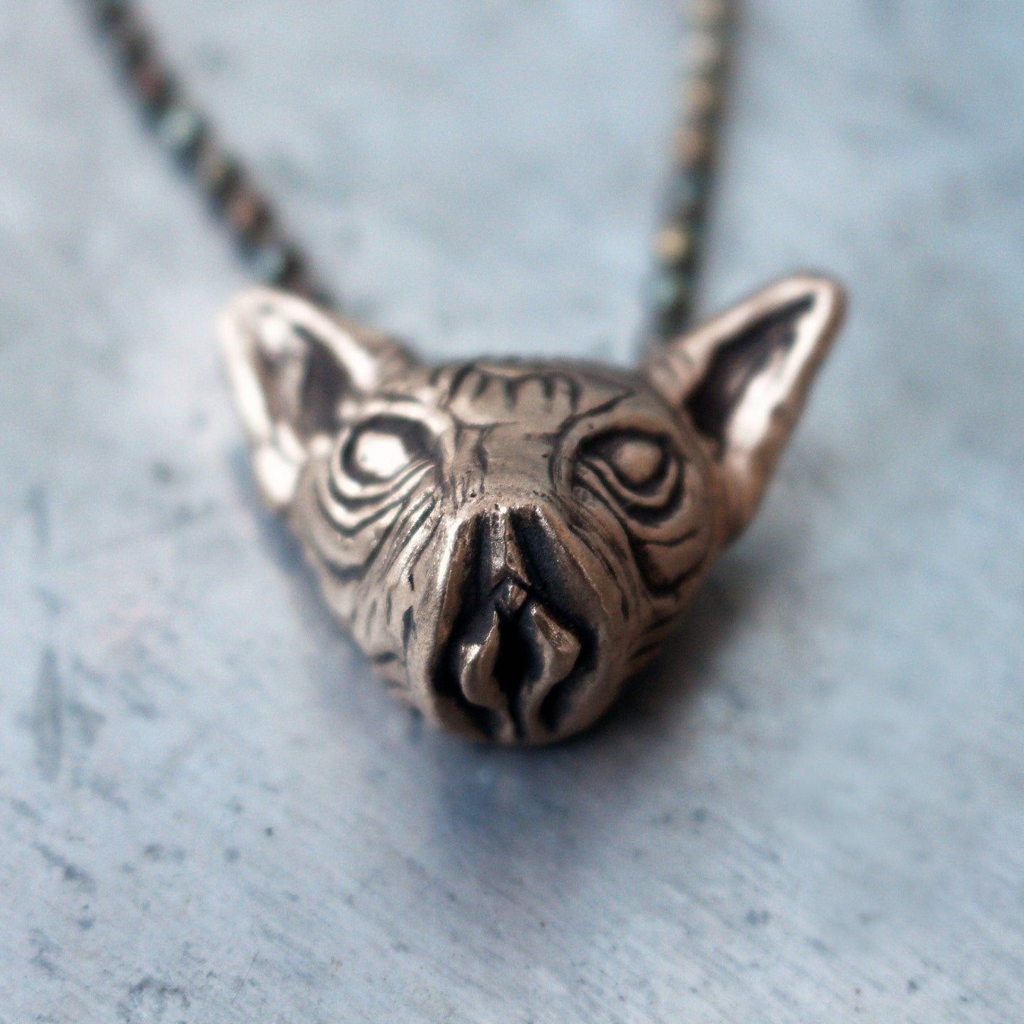 Bronze kinky cat head pendant on a chain