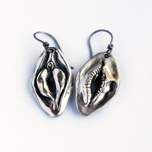 Reversible earrings, one side with a mouth and the other a vulva. Handcrafted in sterling silver with titanium hooks