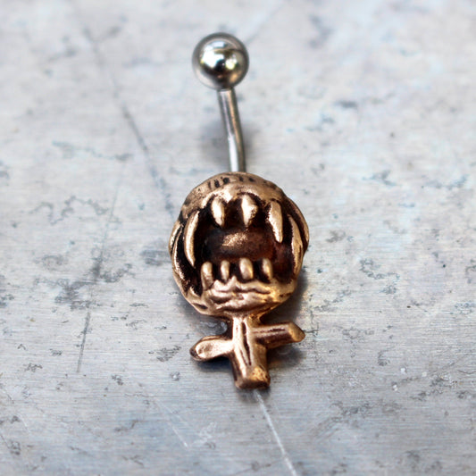 A belly button ring with a bronze feminist symbol design, featuring a barbell with either titanium or surgical steel material.