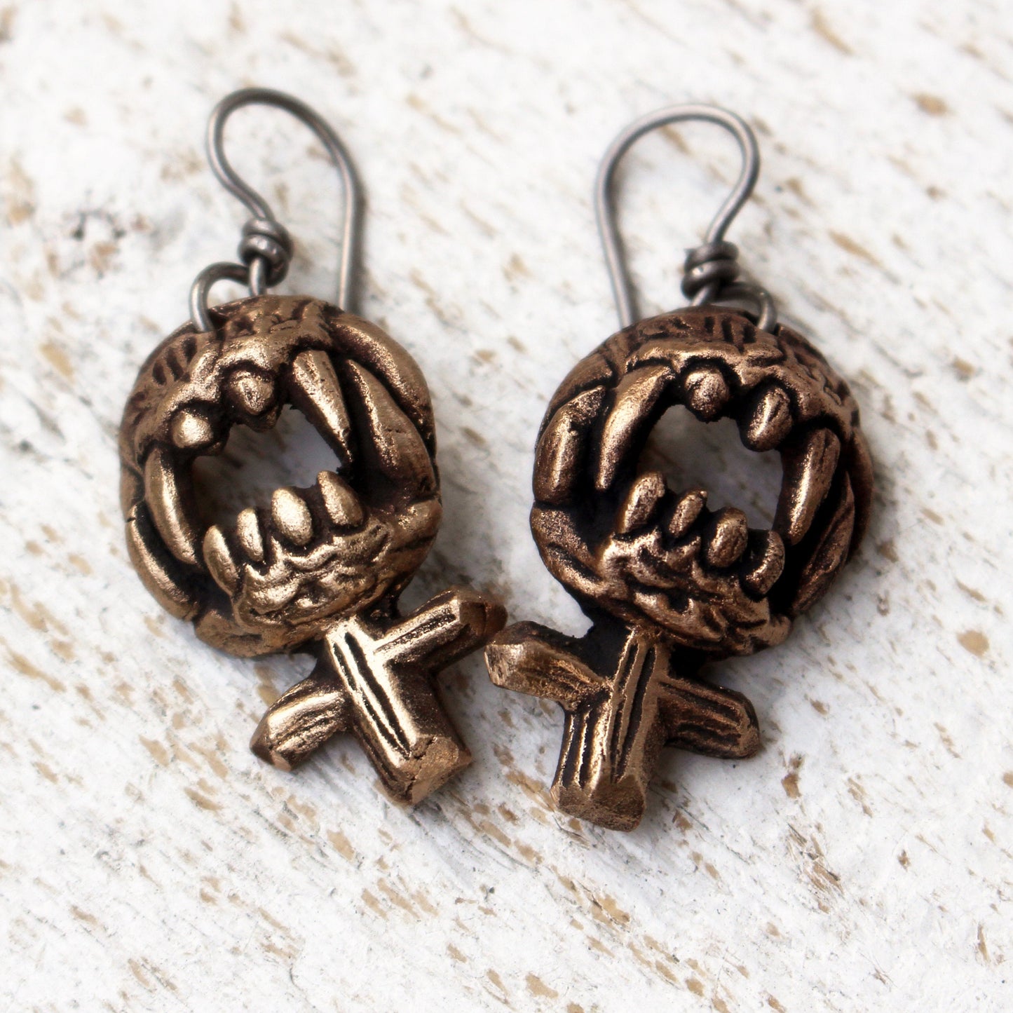 wild womman feminist sign earrings with sharp teeth ready to bite, handforged in bronze with titanium hooks