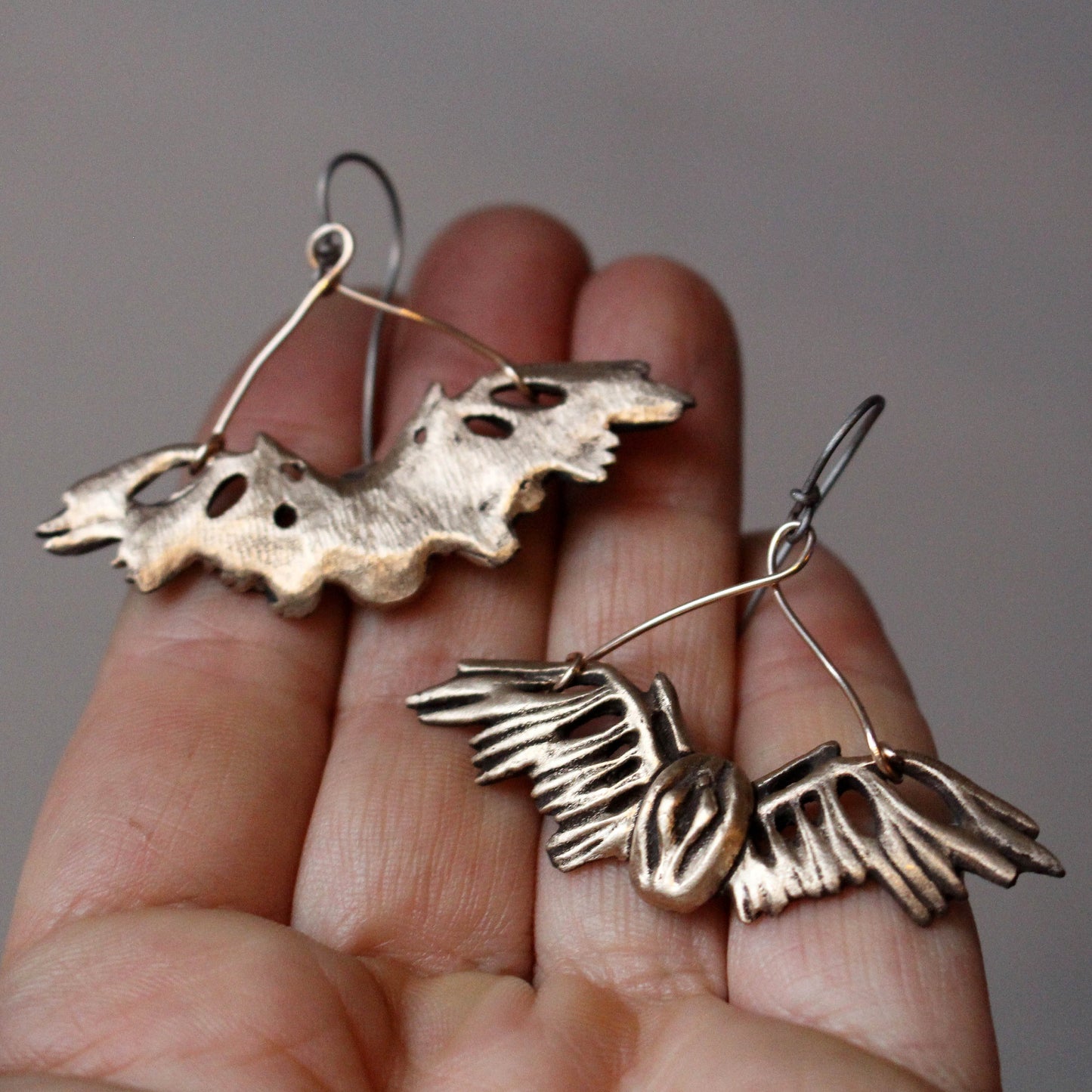a pair of distinctive earrings featuring winged pussys, female genetalia,  Crafted from bronze with titanium wire hooks